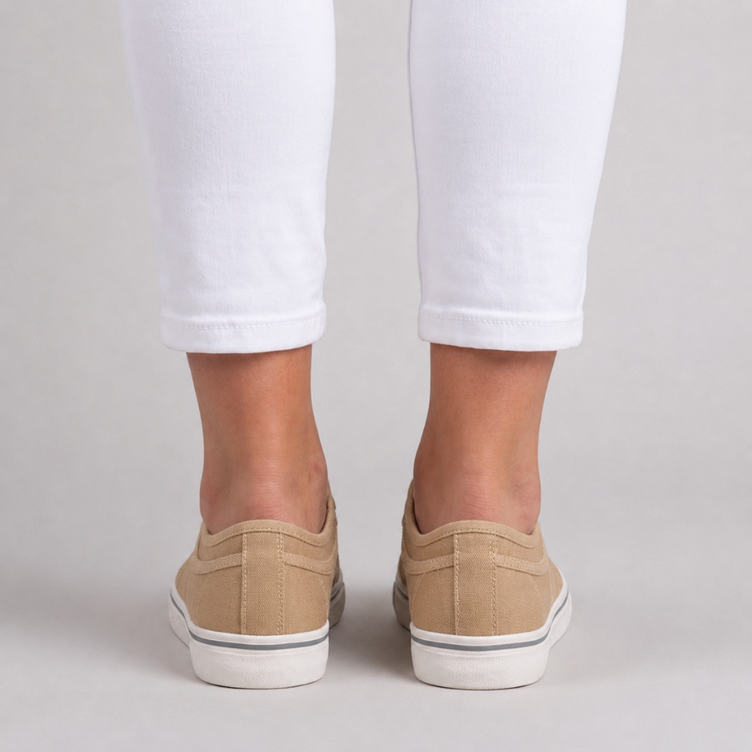 Retro delle sneakers beige indossate, talloncino basso e bordino grigio sul fondo bianco