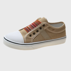 Sneaker beige di profilo su fondo neutro con punta bianca arrotondata e banda a righe