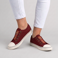 Sneakers donna rosse slip-on indossate con pantaloni bianchi, punta chiara a contrasto