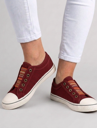 Sneakers donna rosse slip-on indossate con pantaloni bianchi, punta chiara a contrasto