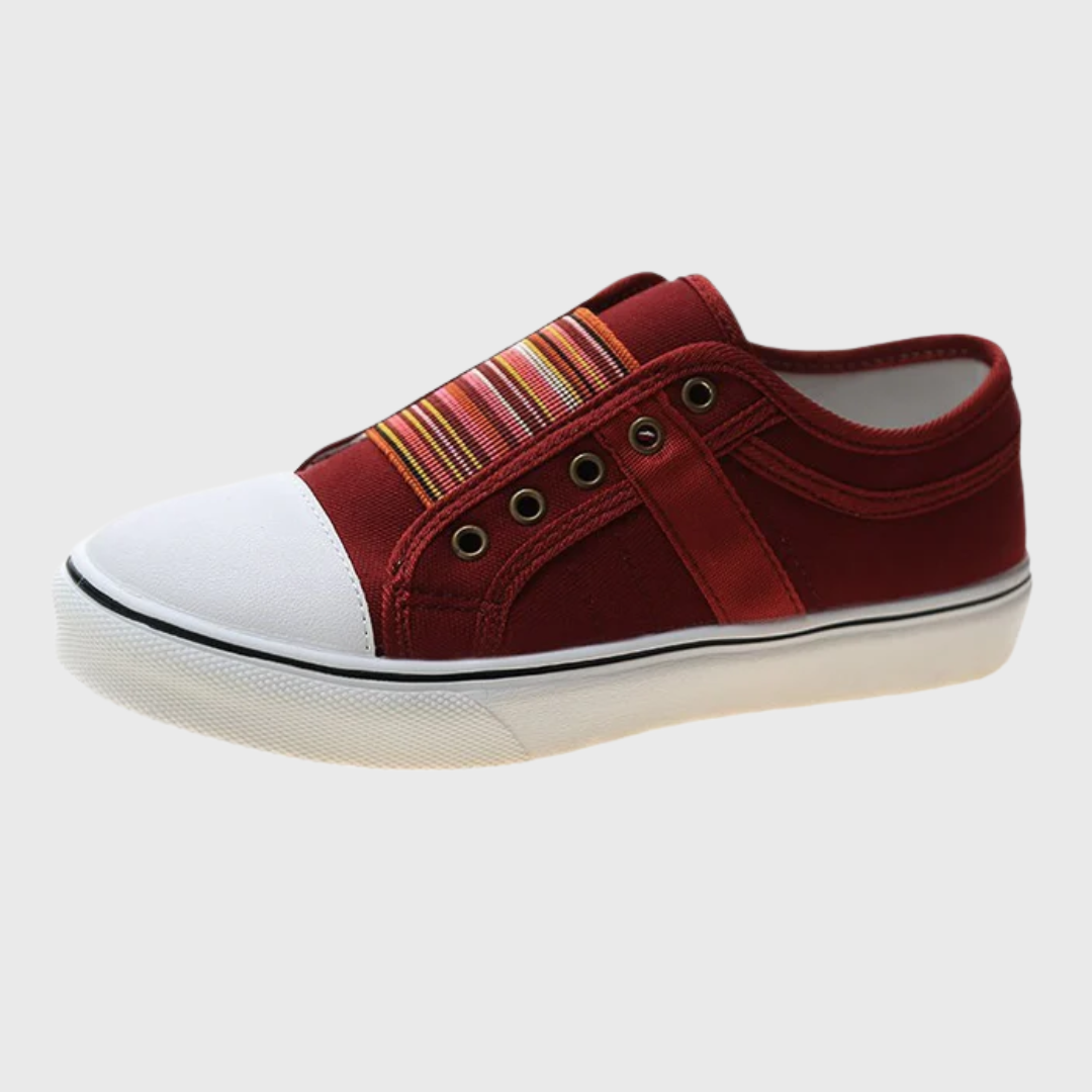 Sneaker rossa di profilo con inserto elastico a righe, occhielli brunati e fondo bianco