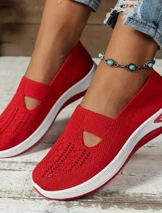 Sneakers rosse donna traforate indossate, profilo della suola bianco a contrasto