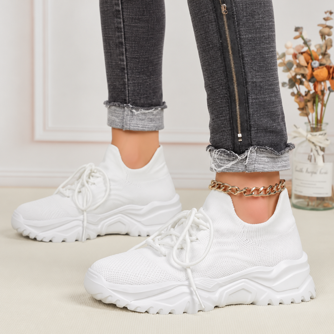 Sneakers bianche donna di profilo con spessa suola platform dentellata bianca