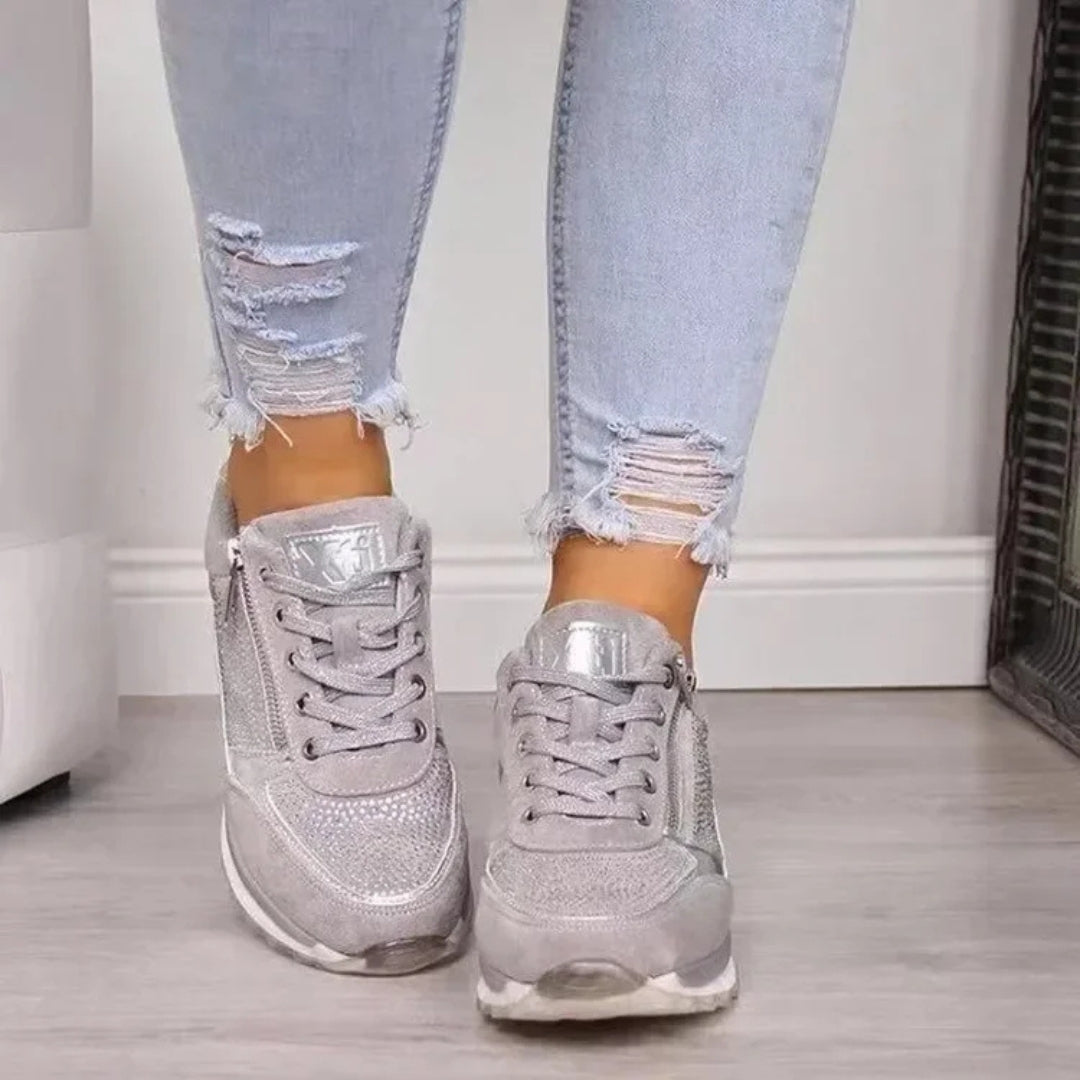 Sneakers donna grigie indossate con pantaloni chiari, strass sulla punta e lacci larghi
