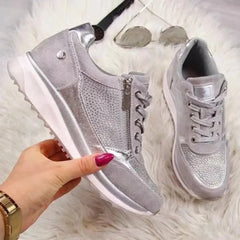 Coppia di sneakers grigie con zip laterale e inserti lucidi su tappeto bianco