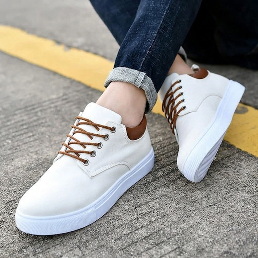 Sneakers bianche uomo con suola bianca zigrinata, piede sollevato sul bordo strada