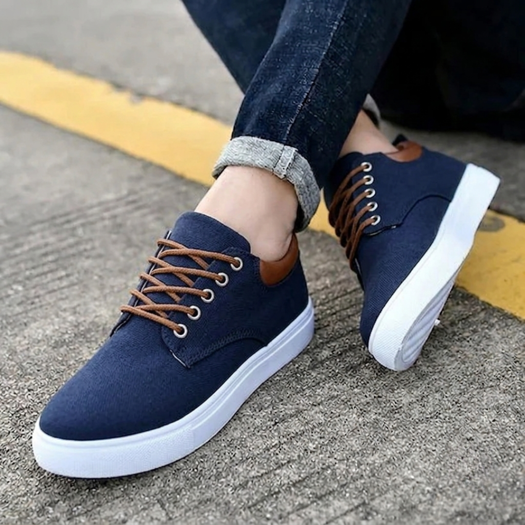 Sneakers blu navy uomo con suola bassa bianca, piede sollevato sul bordo strada