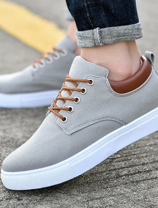 Sneaker uomo bassa grigia con lacci marroni e suola bianca, vista laterale