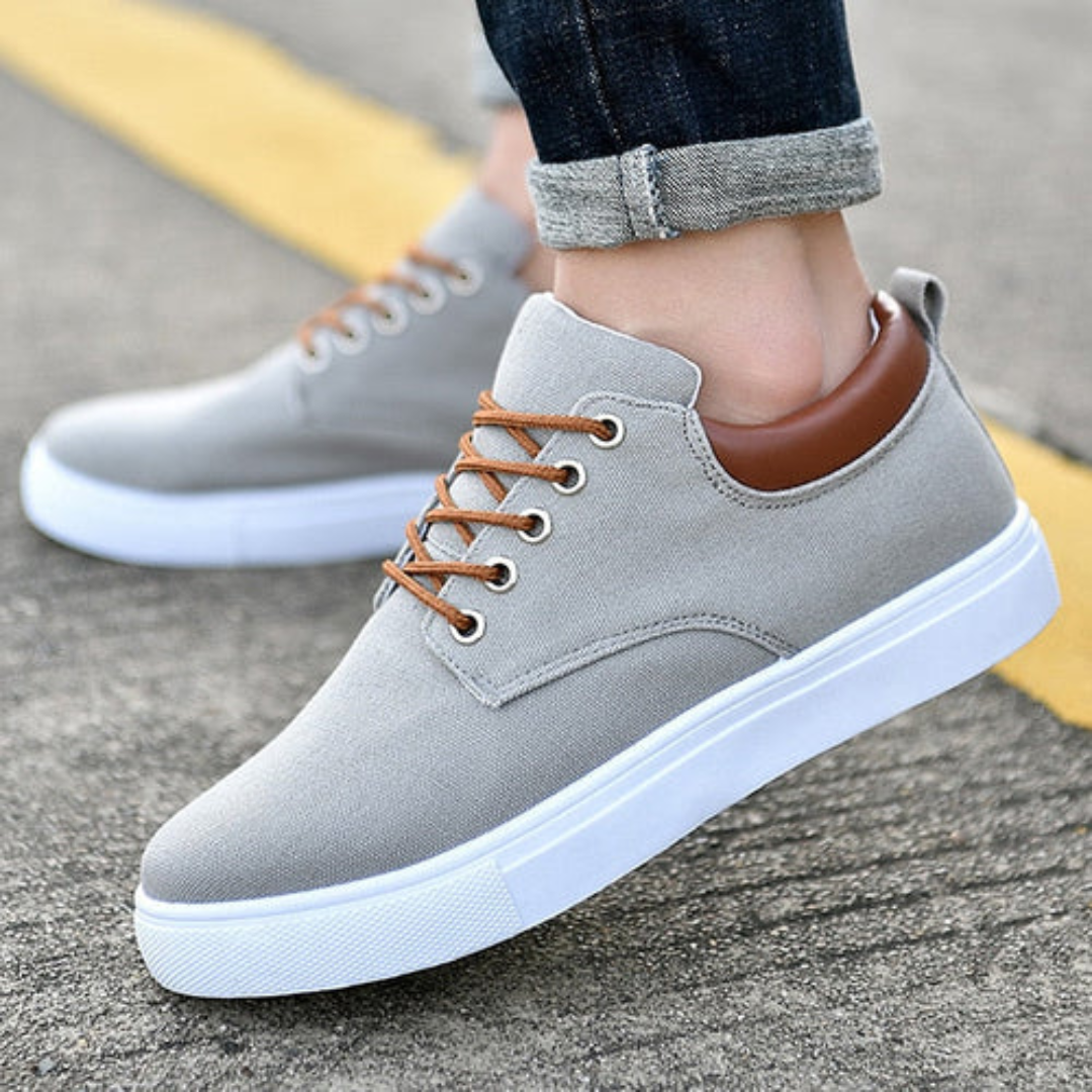 Sneaker uomo bassa grigia con lacci marroni e suola bianca, vista laterale