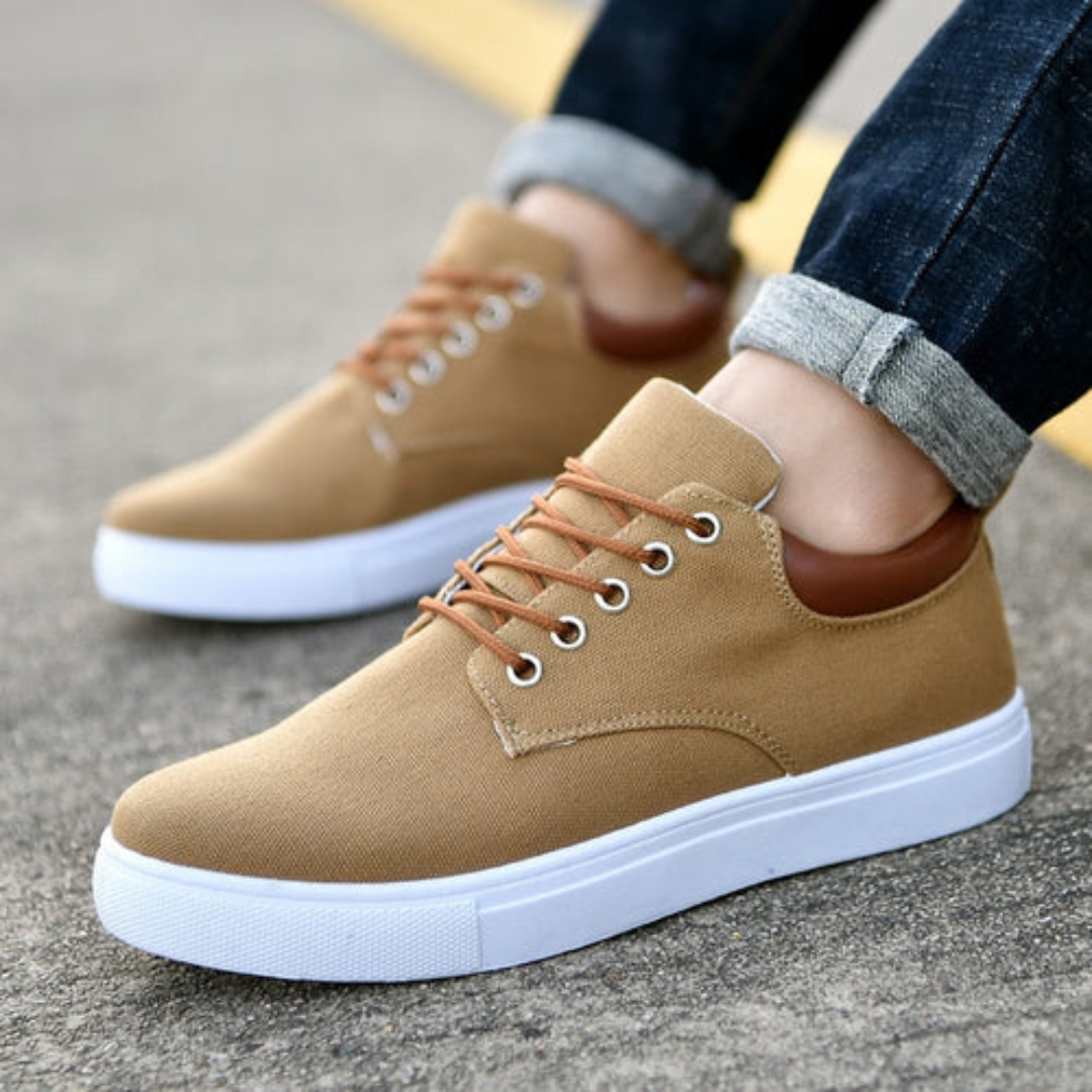 Sneakers marroni da uomo indossate con pantaloni risvoltati, cuciture laterali a onda