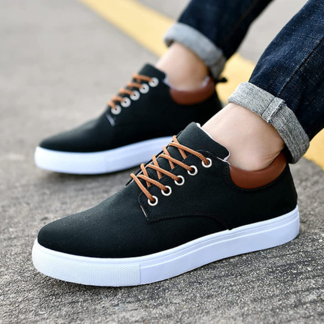 Sneakers nere da uomo indossate con pantaloni risvoltati, tallone lucido marrone