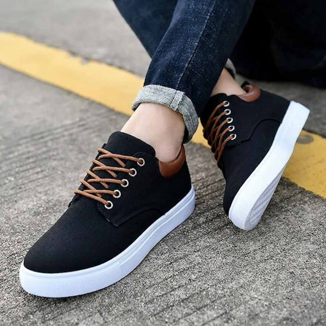 Sneakers nere uomo con suola bianca zigrinata, piede appoggiato sul cordolo