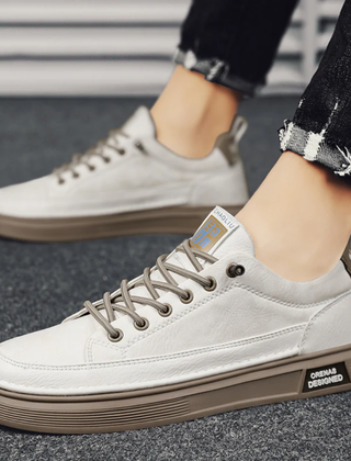 Sneakers uomo beige basse indossate con pantaloni neri e suola scanalata a contrasto