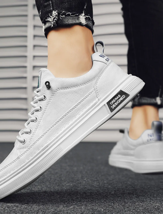 Sneakers uomo bianche basse indossate, placca laterale nera e suola scanalata
