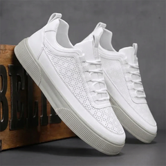 Sneakers uomo bianche appoggiate a una cassa in legno, dettaglio dei fori laterali