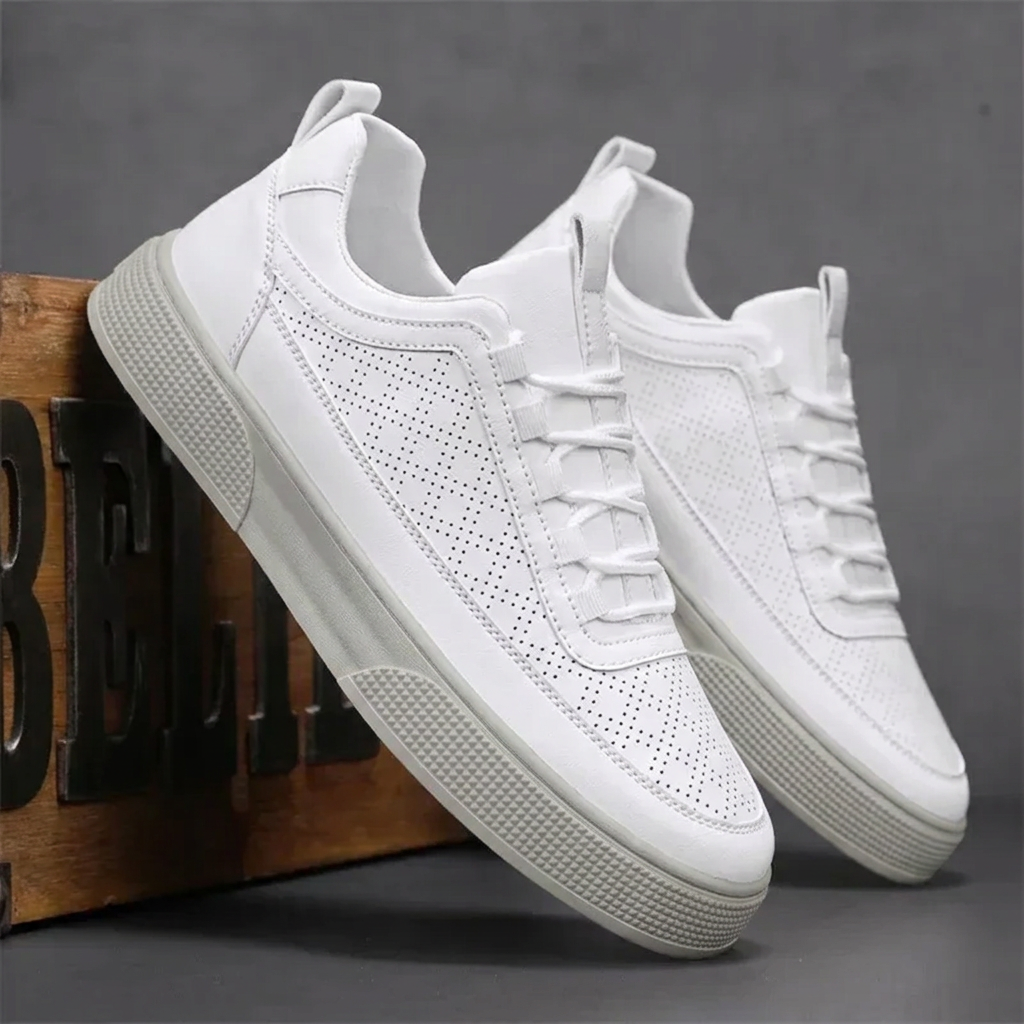 Sneakers uomo bianche appoggiate a una cassa in legno, dettaglio dei fori laterali