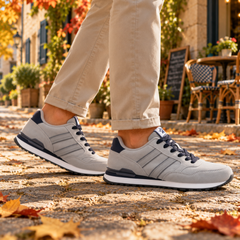 Sneakers grigie da uomo di profilo con inserto blu sul tallone e suola bianca
