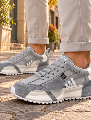 Sneakers uomo grigie con inserti bianchi, rete laterale e suola dentellata bianca