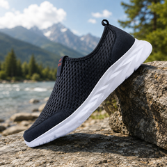 Sneakers uomo slip-on blu traforate con suola bianca appoggiate su roccia