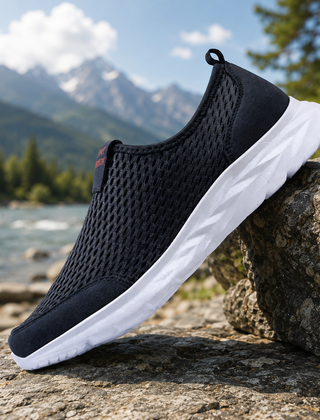 Sneakers uomo slip-on blu traforate con suola bianca appoggiate su roccia