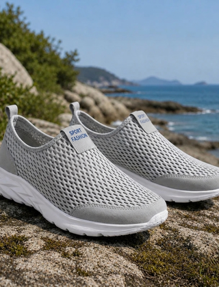 Sneakers uomo slip-on grigie con tomaia traforata e suola bianca su roccia
