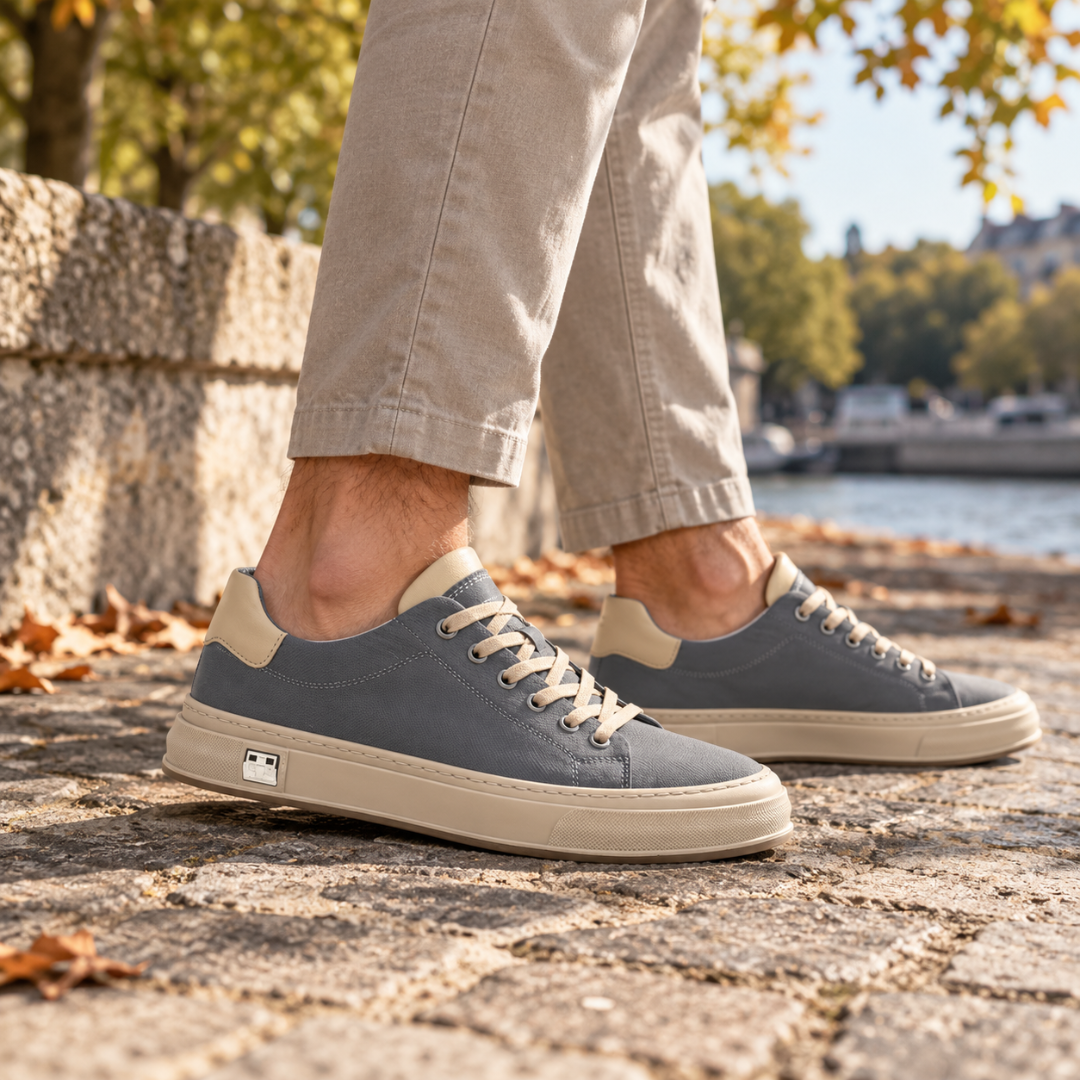 Sneakers basse grigie viste di lato con placchetta metallica sulla suola chiara