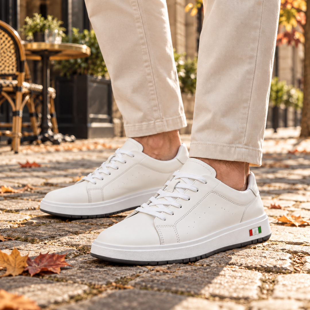 Sneakers uomo bianche con lacci e suola bicolore indossate su pavimentazione in pietra