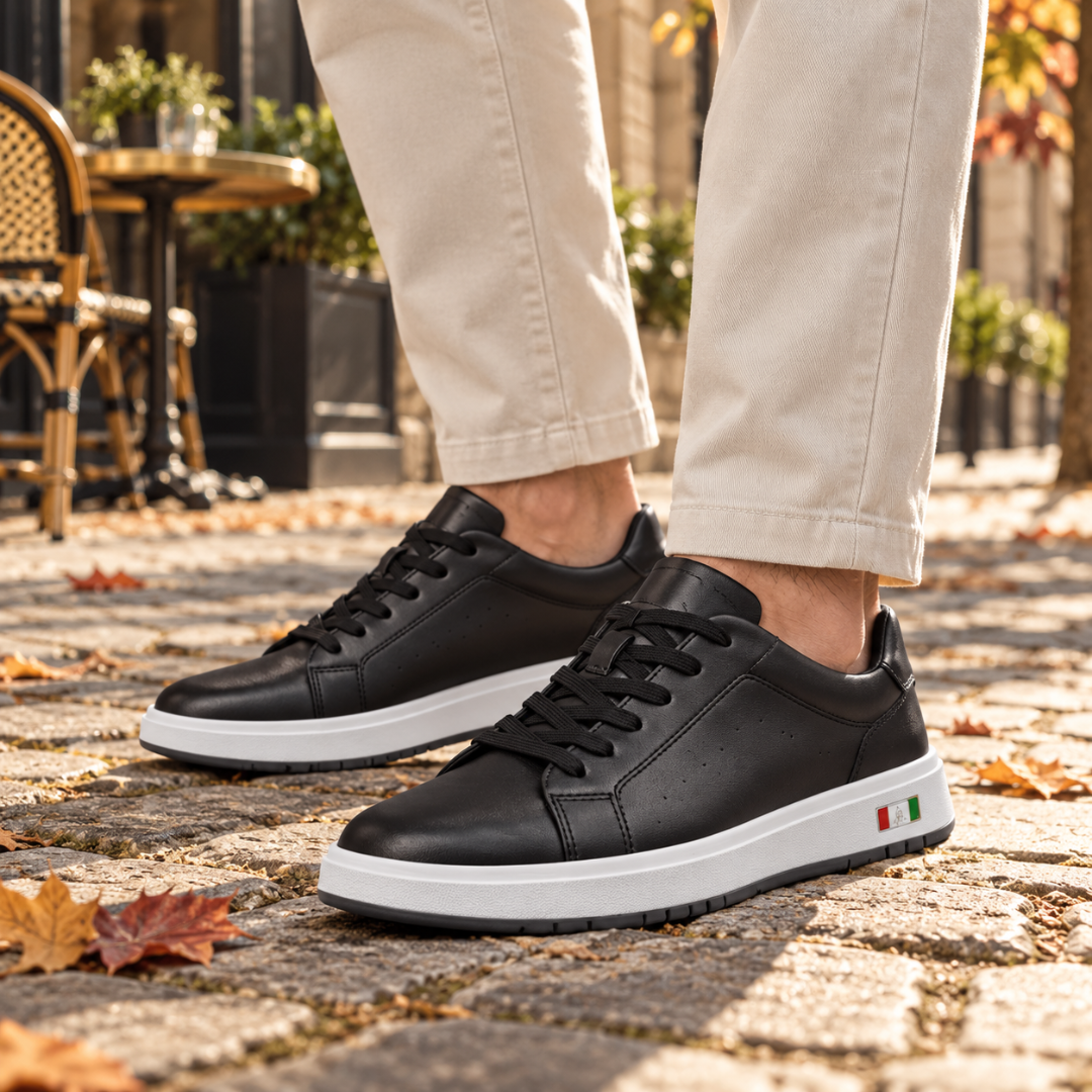 Sneakers uomo nere indossate con pantaloni beige su pavimentazione autunnale