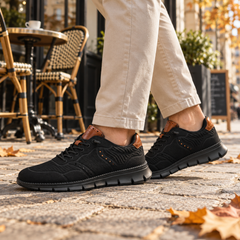 Sneakers uomo nere indossate con pantaloni chiari, dettaglio dei lacci stringati