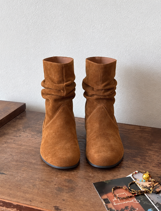 Stivaletti donna color caramello con gambale arricciato, vista frontale su tavolo in legno
