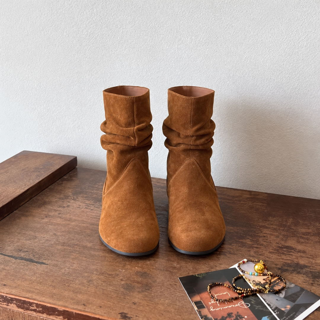 Stivaletti donna color caramello con gambale arricciato, vista frontale su tavolo in legno
