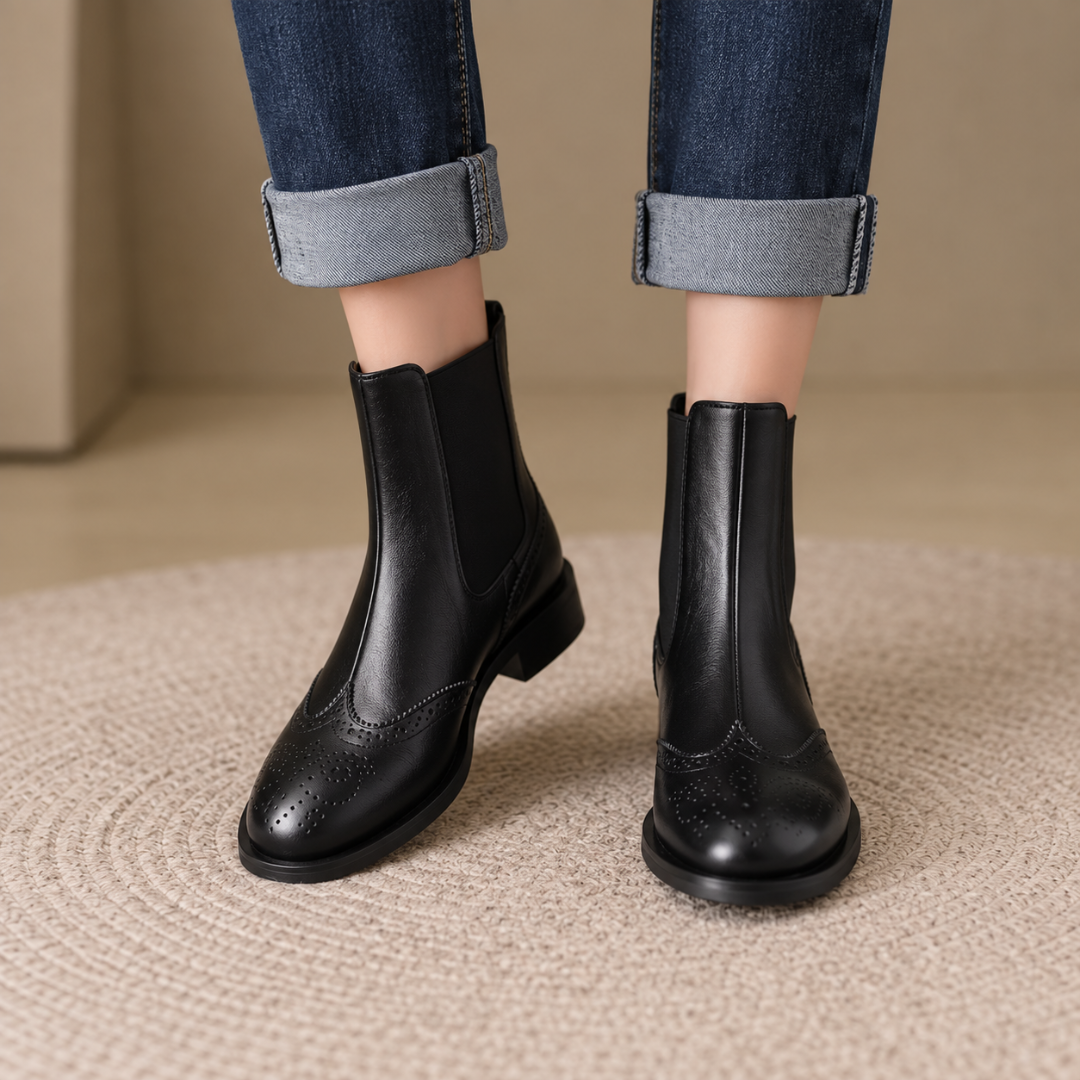 Vista frontale degli stivaletti neri Chelsea con elastici laterali e decori brogue