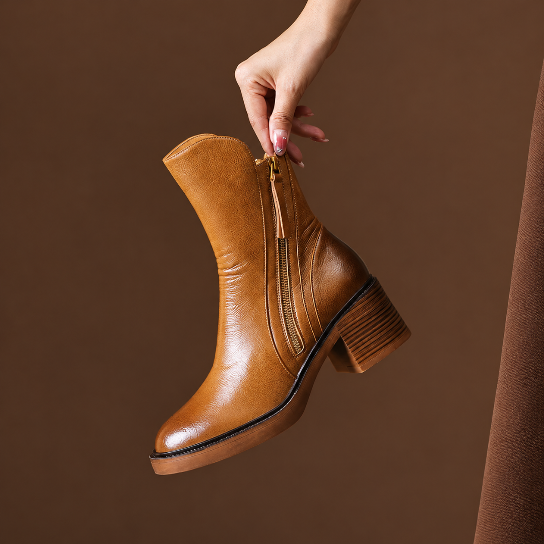 Stivaletto donna marrone tenuto in mano, zip laterale con nappine e punta tonda