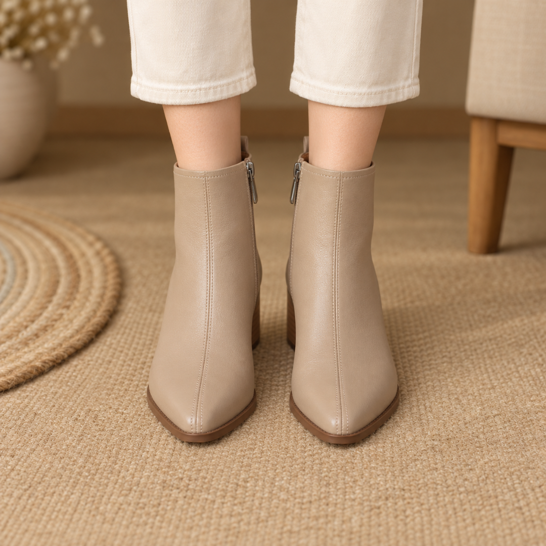 Vista frontale degli stivaletti beige con cuciture verticali e zip laterale con cursore metallico