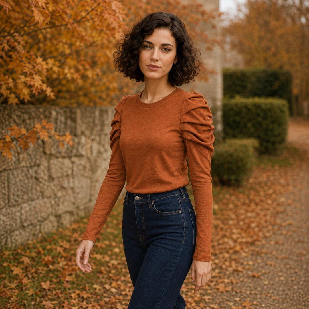 Donna cammina indossando top arancione a maniche lunghe e pantaloni scuri