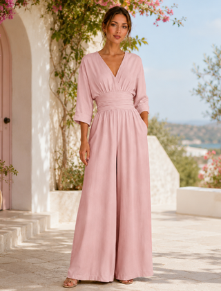 Tuta rosa cipria con vita drappeggiata indossata all'aperto tra fioriture mediterranee