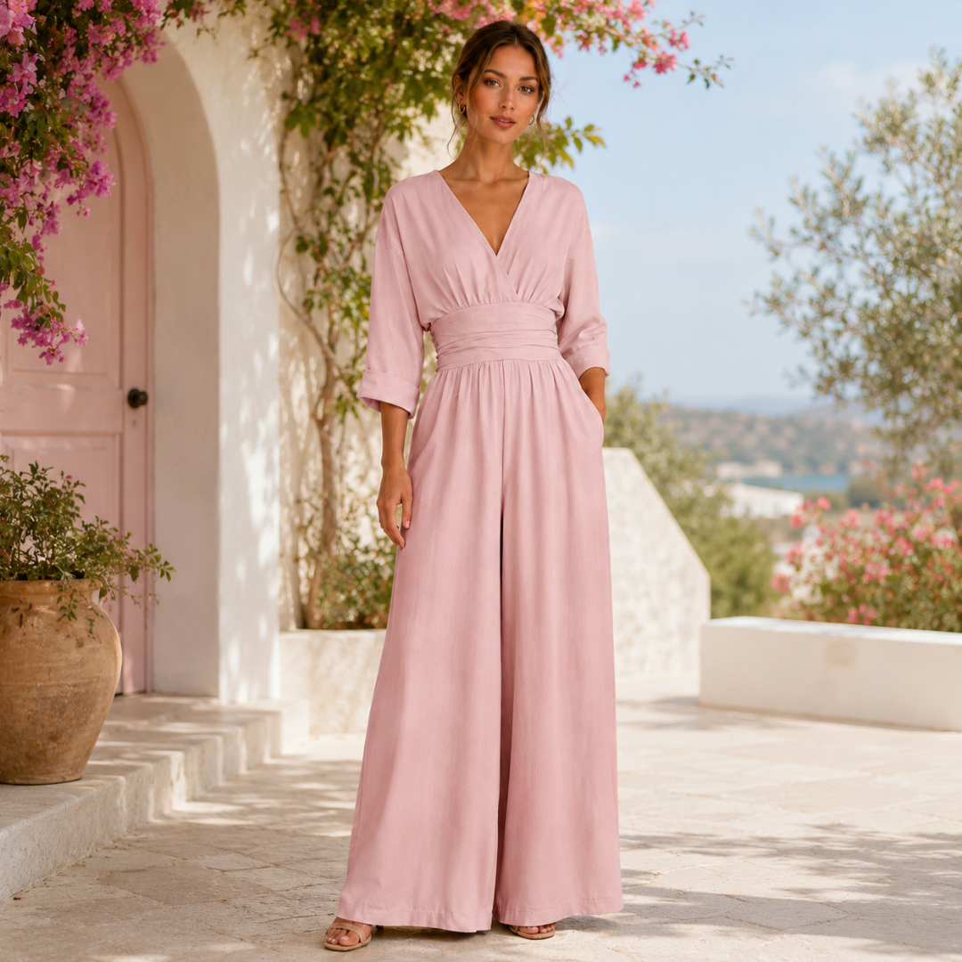 Tuta rosa cipria con vita drappeggiata indossata all'aperto tra fioriture mediterranee