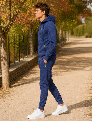 Tuta sportiva uomo blu di profilo, giacca con cappuccio e tasche con zip
