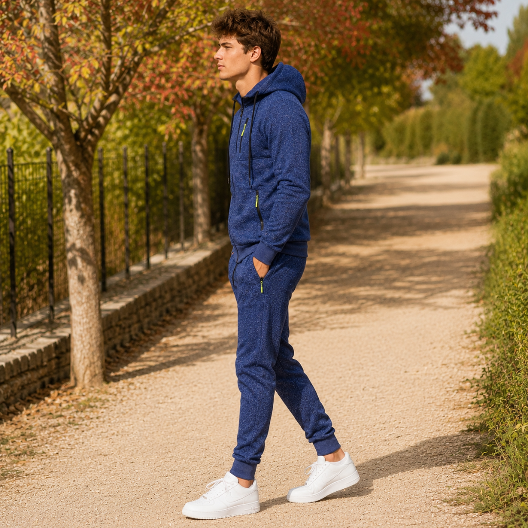 Tuta sportiva uomo blu di profilo, giacca con cappuccio e tasche con zip