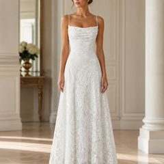 Vestito lungo bianco con corpetto drappeggiato e decoro floreale traforato in sala luminosa
