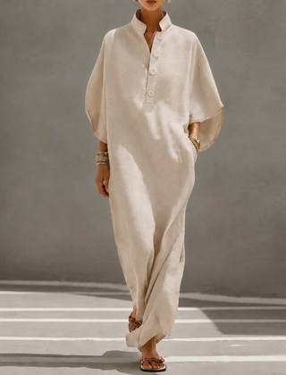 Vestito lungo beige oversize con maniche a pipistrello e abbottonatura frontale, indossato con sandali