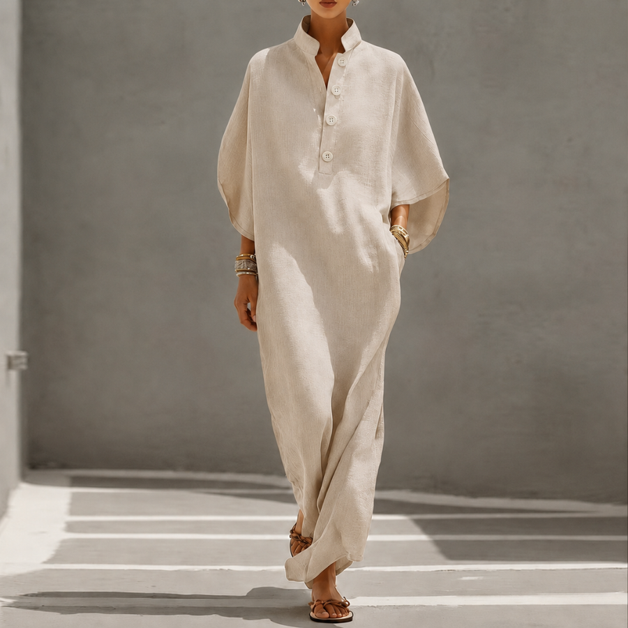 Vestito lungo beige oversize con maniche a pipistrello e abbottonatura frontale, indossato con sandali