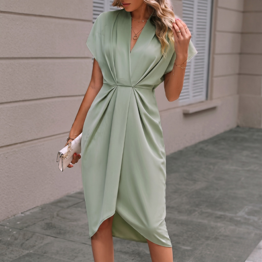 Donna con vestito midi verde chiaro drappeggiato, orlo asimmetrico e pochette bianca